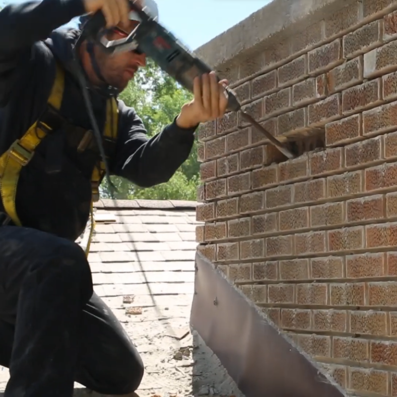 Technician tuckpointing mortar joints between chimney bricks