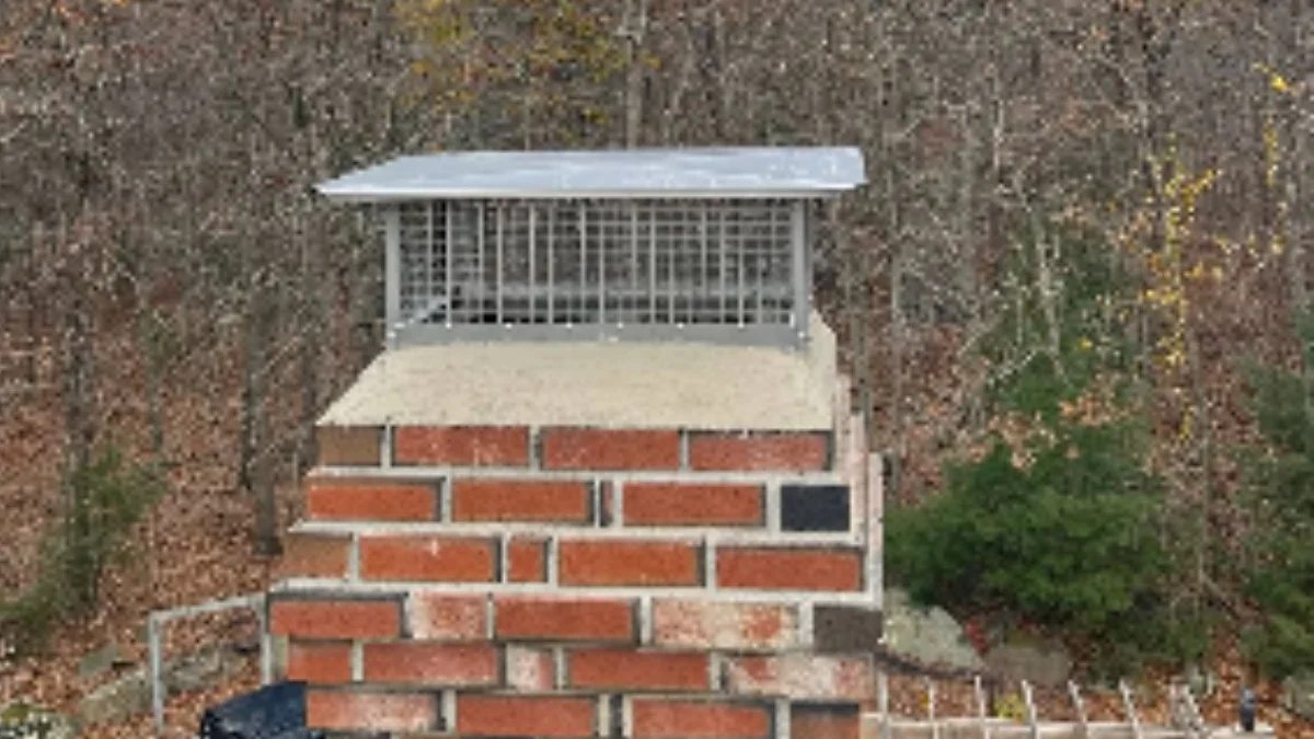A stainless steel multi-flue chimney cap installed on a brick stack