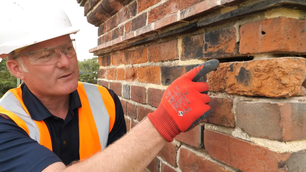 Masonry chimney repair technician working on brick chimney stack